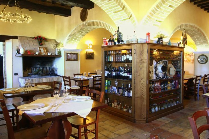 Interior of a restaurant with wooden tables and a well-stocked wine cellar, perfect for gatherings.