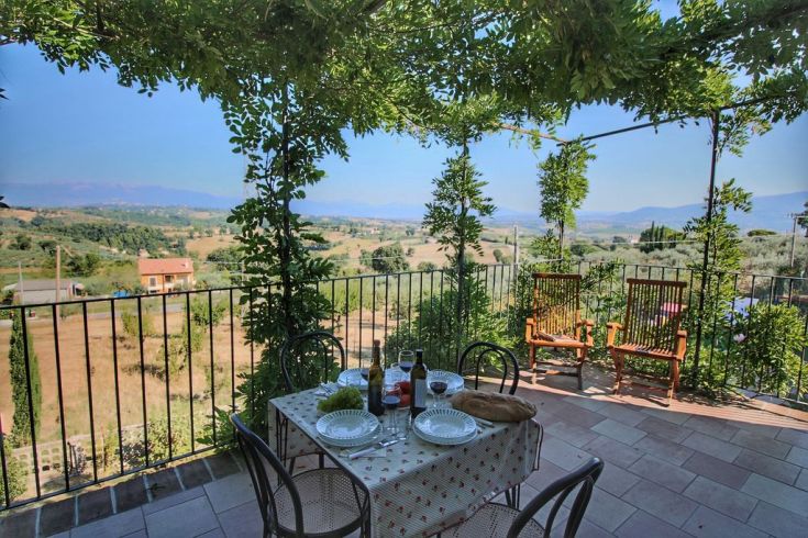 A panoramic view of hills and vineyards, featuring a table set for an outdoor meal.