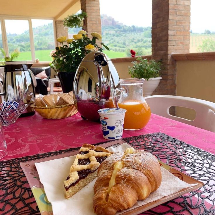 Colazione abbondante con dolci, caffè e succo, affacciata sulla campagna umbra.