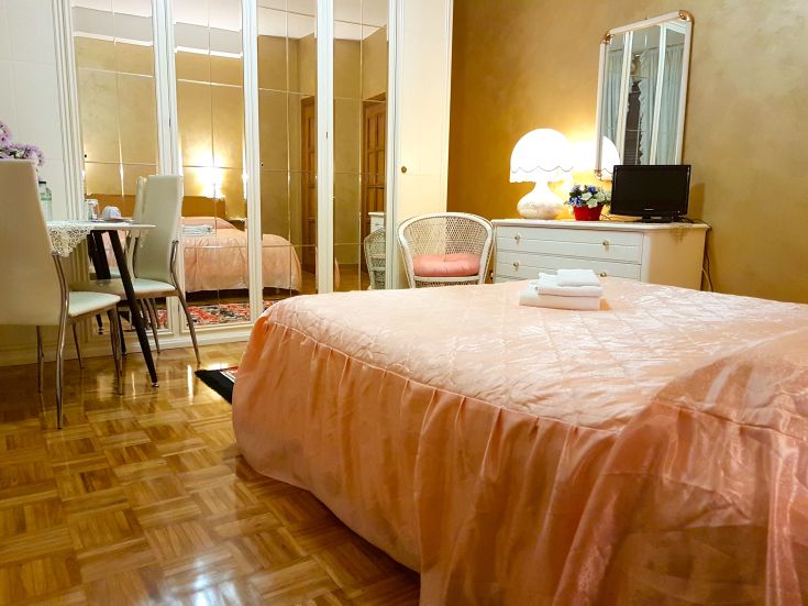 Camera semplice con letti rosa, un divano e una piccola zona pranzo in un bed and breakfast di Orvieto.