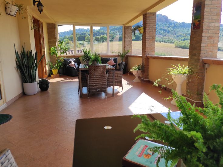 Terrazza con arredamento in rattan e piante, adatta per momenti di relax e colazione nella quiete della campagna.