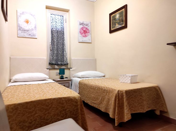 Camera semplice con letti singoli e decorazioni sobrie, adatta per un soggiorno tranquillo.