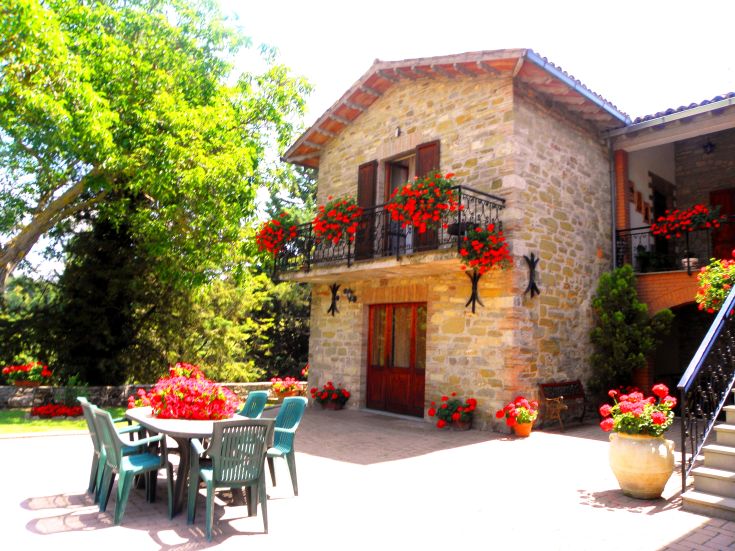 A farmhouse surrounded by greenery, with colorful flowers and tranquil areas for relaxation.