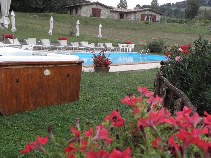 A farmhouse surrounded by greenery, featuring a pool and Jacuzzi area, perfect for relaxing moments in the countryside.