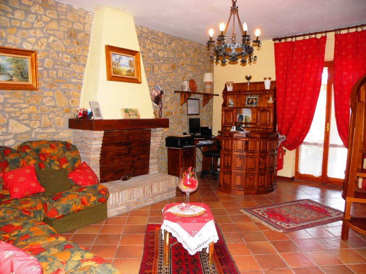 Cozy living room with a fireplace, furnished with rustic elements and warm tones, perfect for relaxing moments.