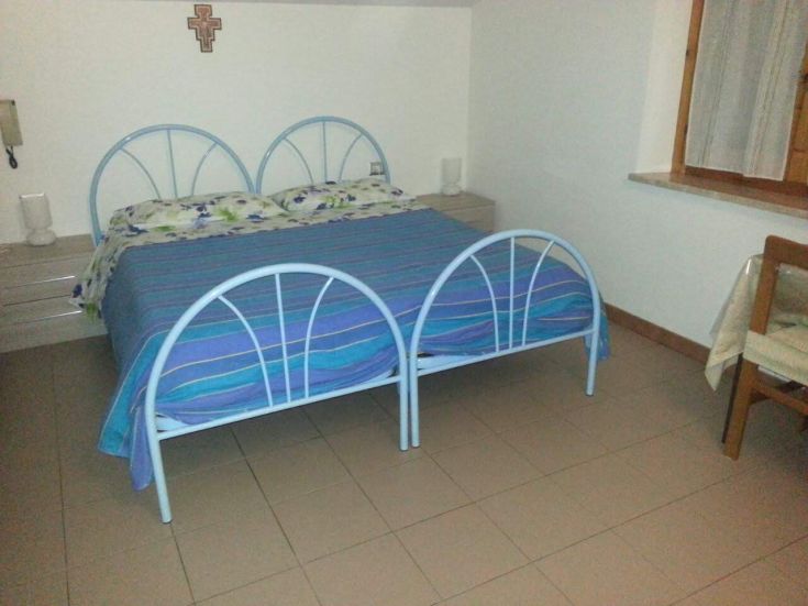 Chambre lumineuse et simple, avec des lits bleus et du linge à rayures. Espace confortable pour les invités.