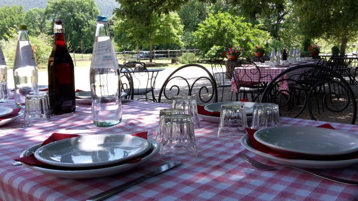 Une table en plein air avec de la vaisselle et des verres, entourée d'un environnement naturel verdoyant.