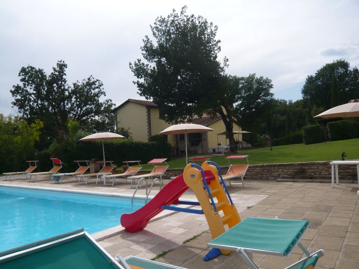 Eine von Bäumen umgebene Villa mit Pool und Spielplatz für Kinder, gelegen zwischen der Toskana und Umbrien.