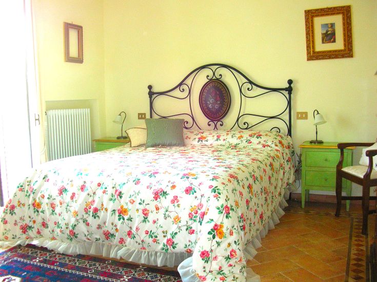 Ein einfaches, gut beleuchtetes Schlafzimmer mit einem Doppelbett und sanften Dekorationen.