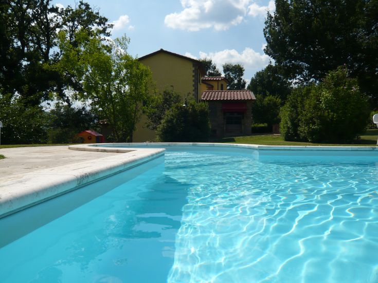 Eine Villa, umgeben von einem geräumigen Garten, mit einem großen Schwimmbad. Ideal für entspannte Familienmomente.