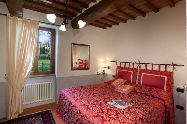 Einfache Schlafzimmer mit Doppelbett und schlichter Einrichtung. Natürliches Licht und ruhiger Ausblick nach draußen.