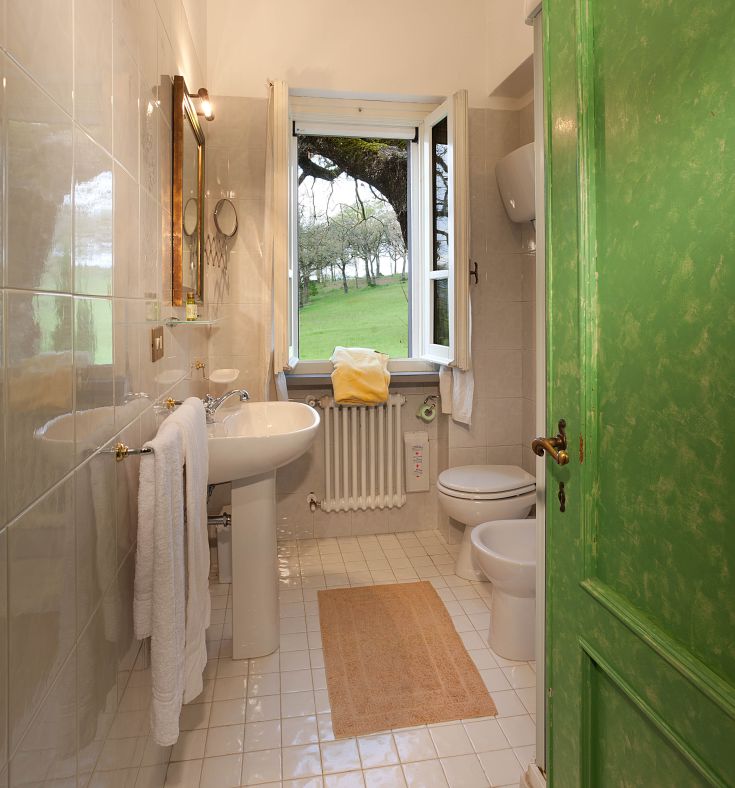 Modernes Badezimmer mit Blick auf den Garten, eingerichtet mit schlichten Design-Accessoires und dezenten Dekorationen.