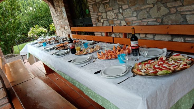 Ein Tisch im Freien mit Essen und Wein, ideal für ein geselliges Treffen.