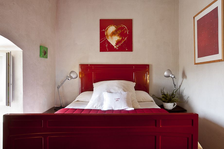 A simple and cozy room featuring a red bed and wall decorations. A corner for relaxation.