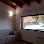 Ein gemütliches Wohnzimmer mit einem Sofa und einem großen Fenster mit Blick auf einen Garten.