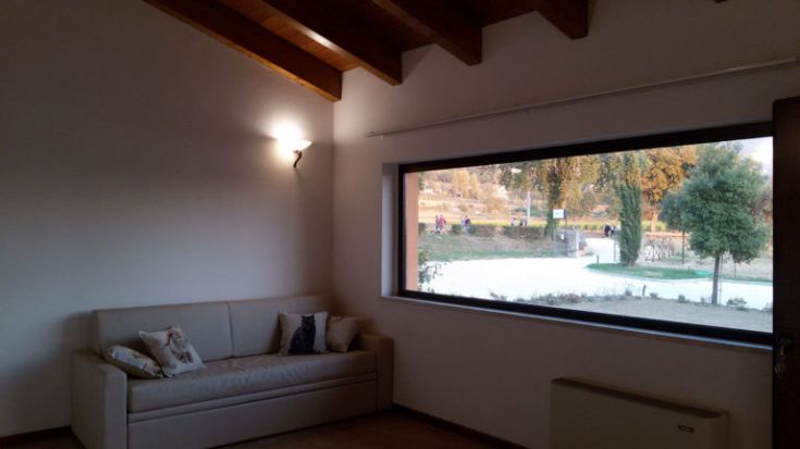 Innenraum eines Gebäudes mit einem Sofa und Blick auf eine natürliche Umgebung.