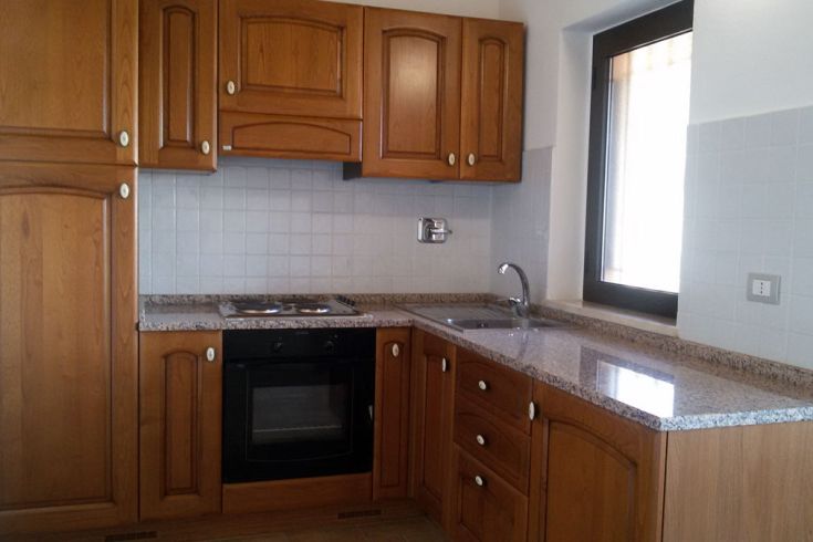 Holzverarbeitete Küche mit Schränken und Granitoberfläche, funktionales und minimalistisches Design.