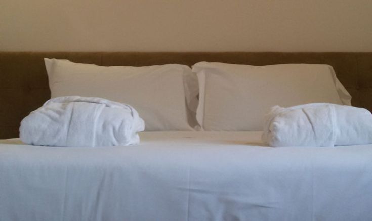 Schlafzimmer mit einem Doppelbett, dekoriert mit weißen Kissen und Handtüchern, ideal für einen ruhigen Aufenthalt.