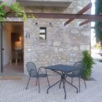 Ein Außenbereich eines Steinhauses, eingerichtet mit einem Tisch und einigen Stühlen.