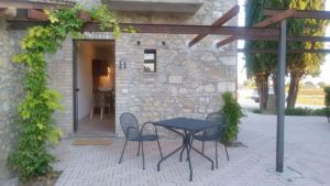 Ein entspannter Außenbereich eines Landhauses, eingerichtet mit einem Holztisch und Stühlen.