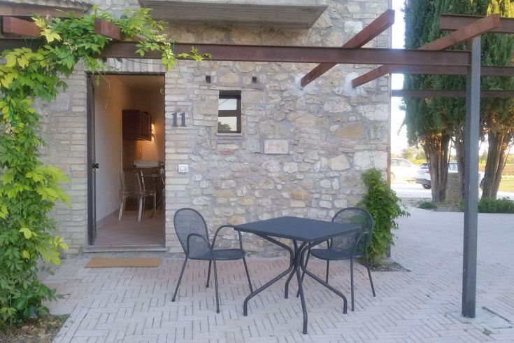 Eingang eines Steinhauses mit einem Tisch und Stühlen im Freien in einer ruhigen Umgebung.