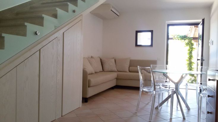 Ein modernes Wohnzimmer mit Sofa und Tisch, mit Blick auf einen gepflegten Garten.