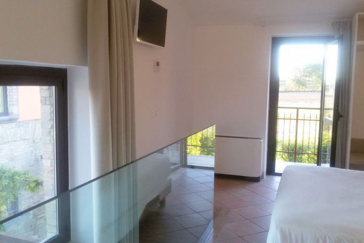 Heller Innenraum eines Schlafzimmers mit Blick auf den Garten und einfacher Einrichtung.