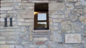 Detail einer Steinfassade mit einem Fenster und der Hausnummer 11.