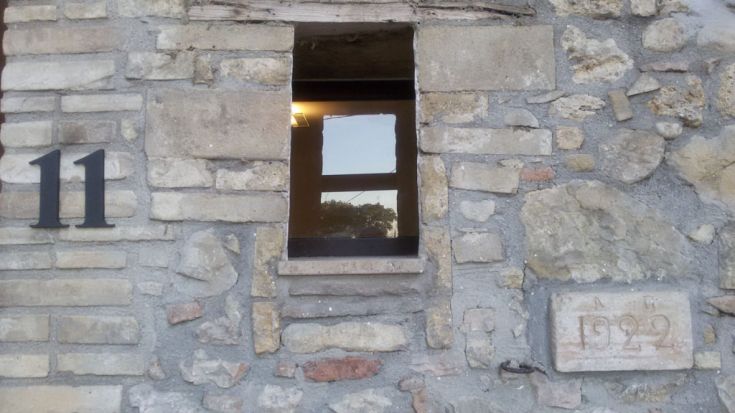 Nahaufnahme einer Steinmauer mit einem Fenster und einem Schild.