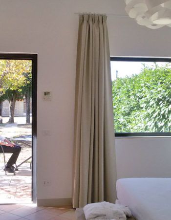 Innenansicht eines gemütlichen Landhauses mit hellem Vorhang und schlichter Atmosphäre.