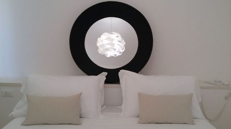 Ein einfacher Schlafzimmer-Innenraum mit einem Bett und einer modernen Lampe.