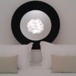 Schlichtes Interieur mit weißen Betten und einem modernen Kronleuchter.