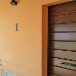 Eingang eines Gebäudes mit einer Holztür und warmen Wandfarben.