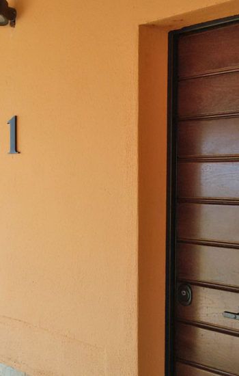 Einfache Tür mit der Zahl 1 auf orangefarbenem Hintergrund, die zu komfortablen Räumen führt.