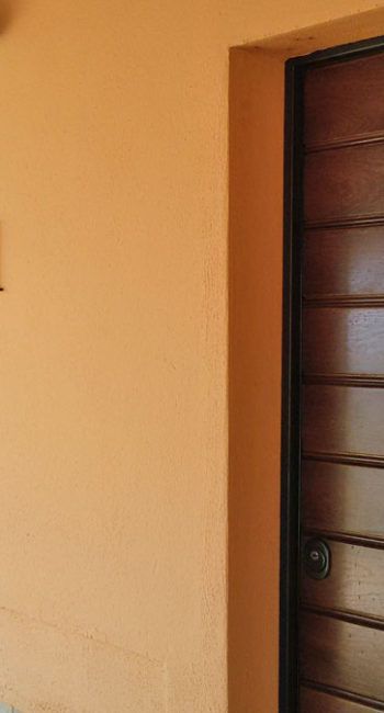 Eine Holztür, die auf eine orange Wand zeigt, und den Beginn von etwas Neuem andeutet.