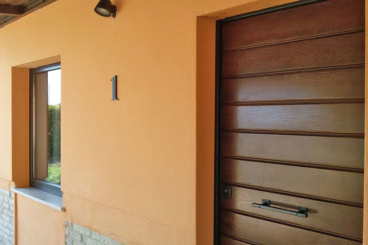 Der Eingang eines Hauses mit einer Holztür und der Hausnummer 1.