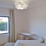 Ein heller Raum mit schlichtem Design, ausgestattet mit großen Fenstern, die sanftes Licht filtern.