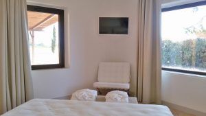 Ein heller und ordentlicher Raum mit aufgestellten Betten und Fenstern, die auf eine grüne Fläche blicken.