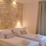 Helle und geräumige Zimmer mit Einzelbetten und Steinwänden.