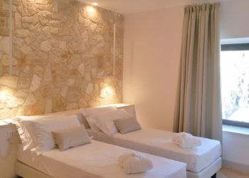 Einfache Schlafzimmer mit zwei Einzelbetten und einer Wand aus Naturstein.