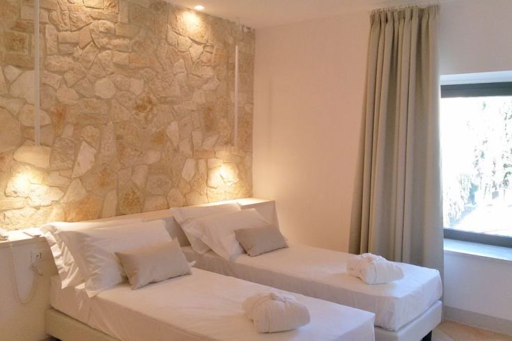 Gemütlicher, gut beleuchteter Raum mit Steinwänden und Einzelbetten.