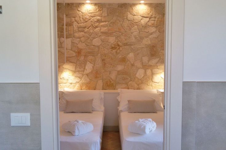 Einfache Zimmer mit Steinwänden und zwei Einzelbetten.