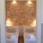 Einfaches Zimmer mit zwei Einzelbetten und einer Steinwand.