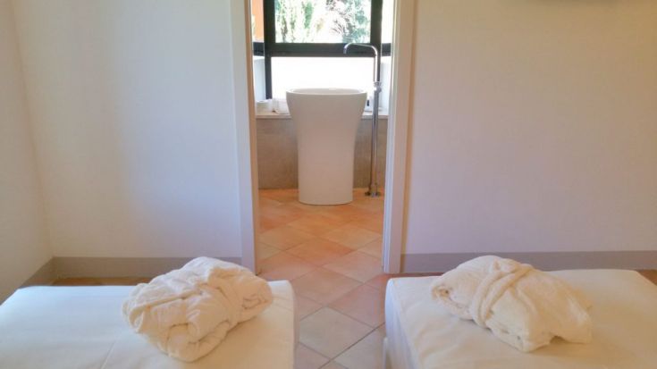 Ruhiges Interieur eines Spa-Zimmers, ausgestattet mit Liegen und Blick auf das Badezimmer.