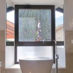 Ein helles Badezimmer mit einem großen Fenster, das den Raum erhellt und eine Aussicht auf die Umgebung bietet.