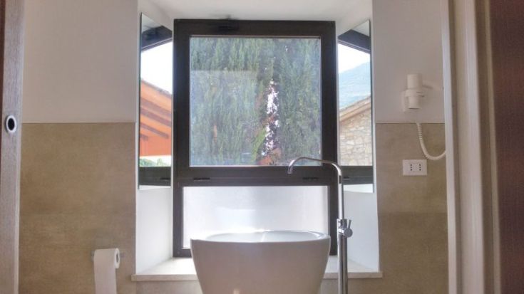 Eine elegante Badezimmer-Szene mit einem großen Fenster, das auf eine Außenansicht zeigt.