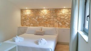 Gemütliches Schlafzimmer mit einer Steinwand und ordentlich angeordneten Betten.