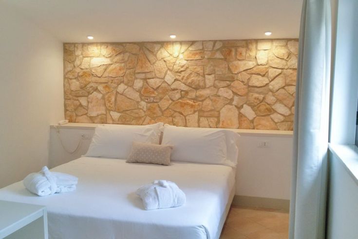 Einfache Zimmer mit Wänden aus Naturstein und bequemen Betten.