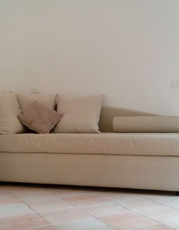 Ein schlichter und bequemer Sofa mit beigen Kissen in einer gut beleuchteten Umgebung.