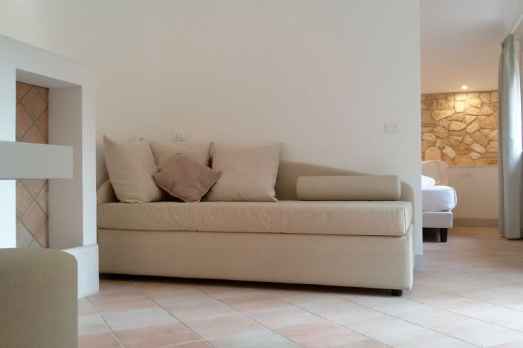 Ein schlichtes Wohnzimmer mit einem Sofa und zeitgenössischen Elementen, durch natürliches Licht beleuchtet.